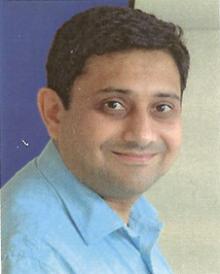 Photograph of Sanjay Morzaria wearing a light blue shirt.