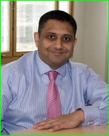 Head and sholder photo of Sanjay Morzaria wearing a blue shirt and pink tie.